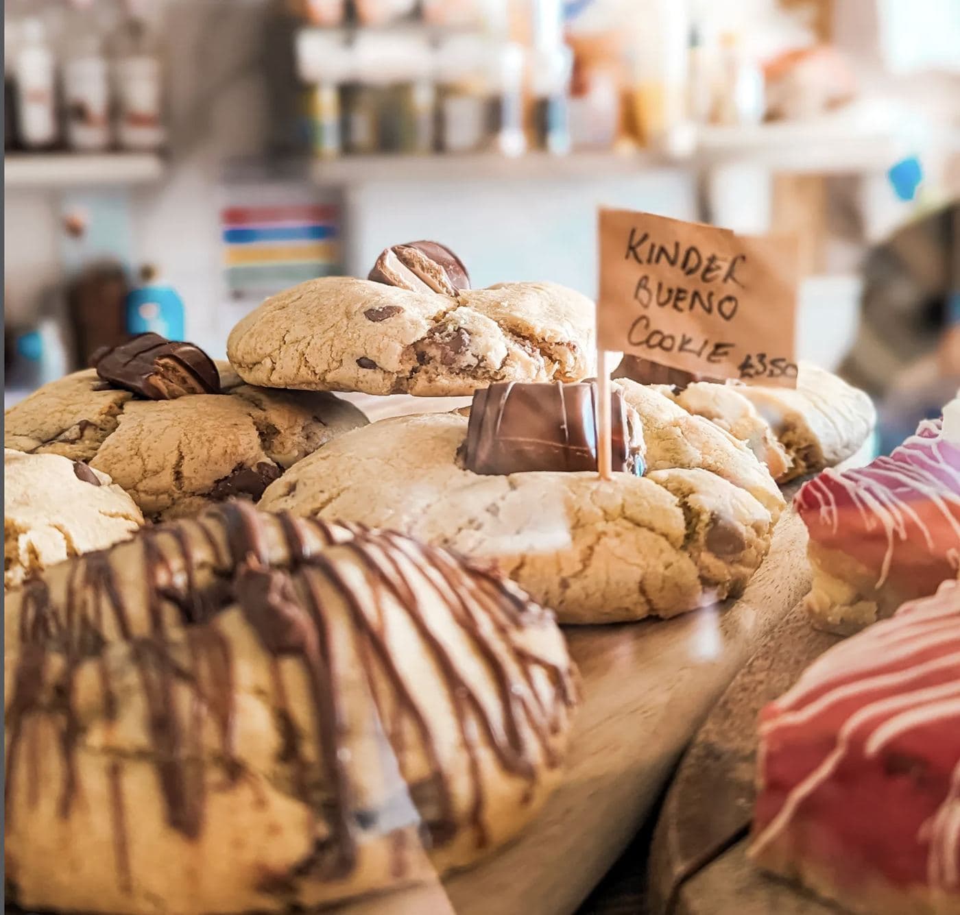 Saltd's house-baked Kinder Bueno cookies stacked on the counter with a handwritten 'Kinder Bueno cookie £3.50' price tag
